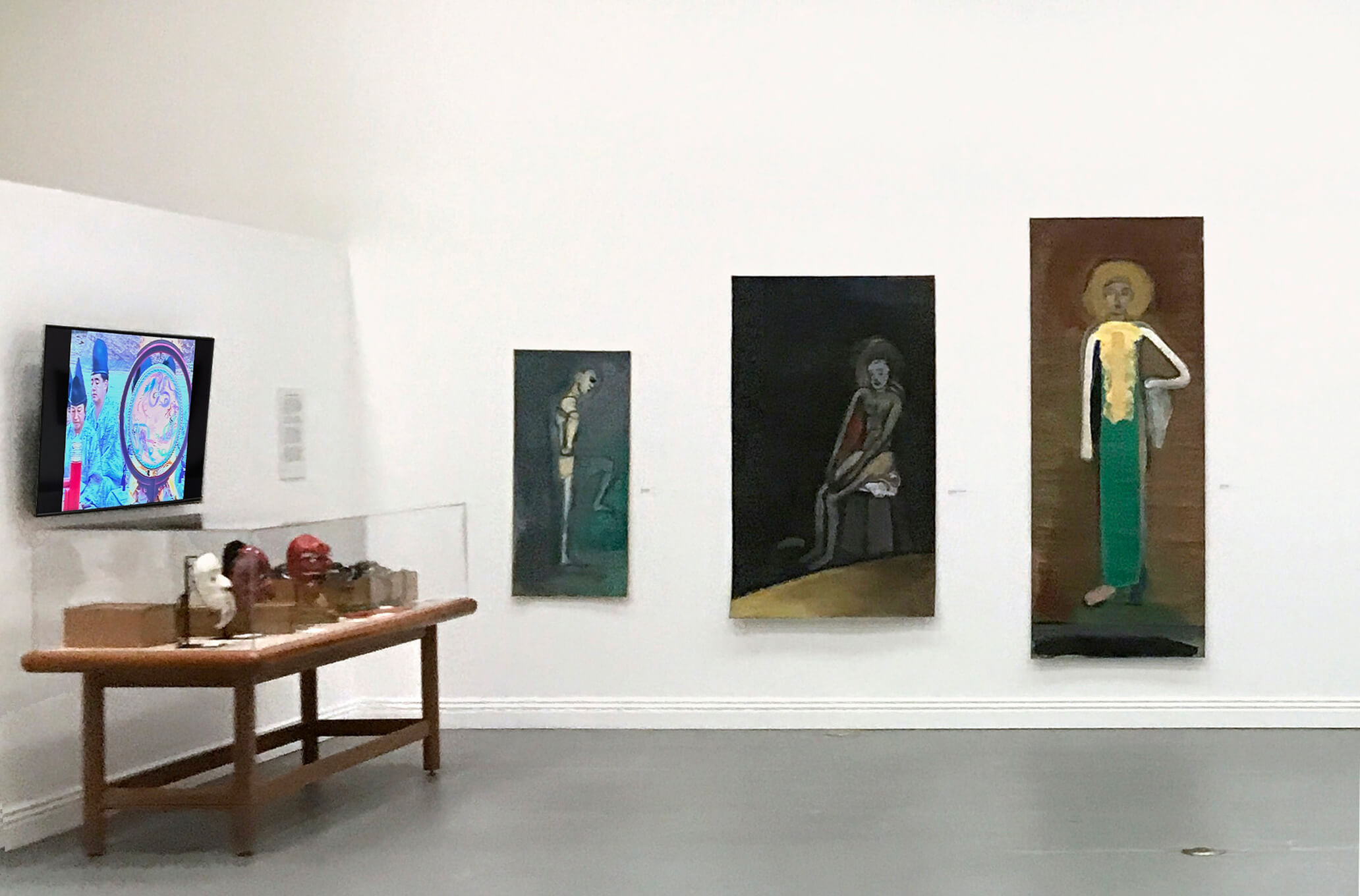 Installation view, Keisho Okayama: Selected Works - On the back wall: Male Dancer, 1978, Seated Figure/Ochre Edge, 1978 and Fayum Figure, 1985, all acrylic on paper. Case containing masks, instruments and boxes to the left.