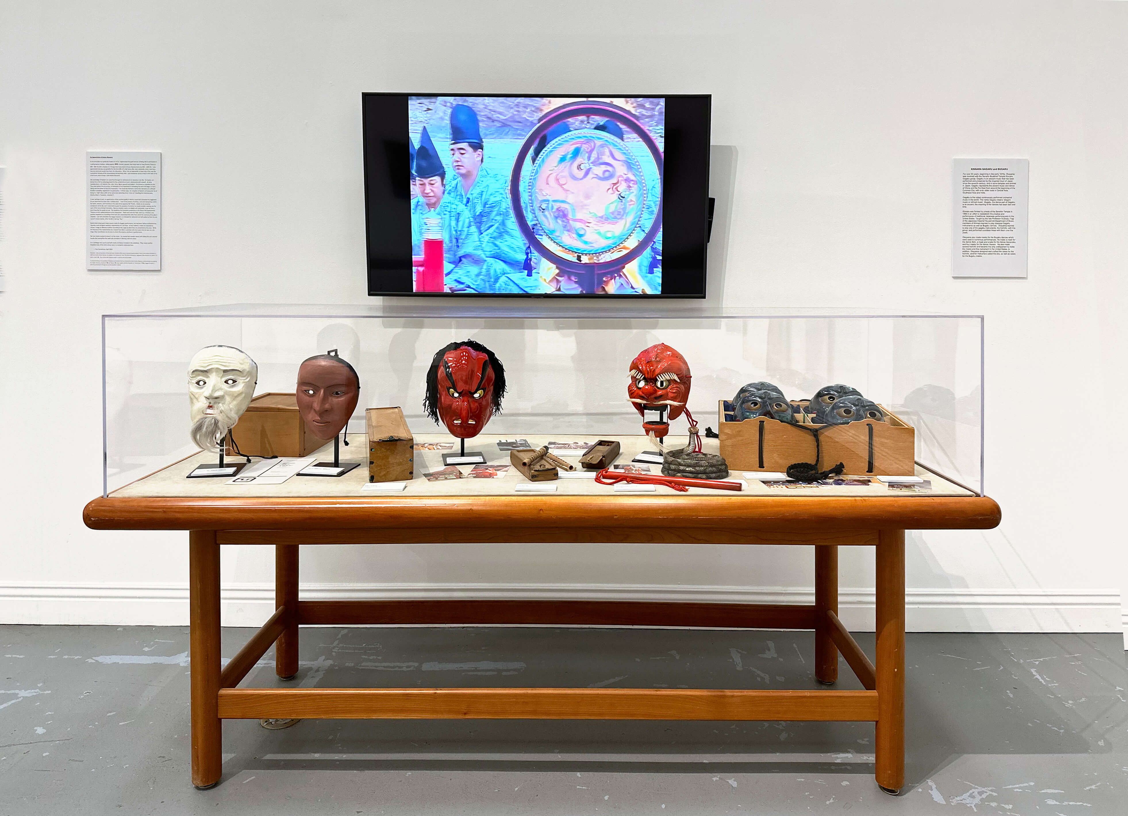 Installation view, Keisho Okayama: Selected Works - Bugaku and Noh Masks, Gagaku instruments and boxes, 1980s. Above, a video of a Kinnara Bugaku performance featuring Okayama’s masks.